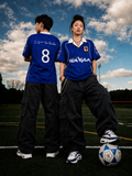 Male and female models wearing the Blue Sakura Football Jersey on a football pitch