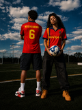 Male and female models wearing the Roja Football Jersey on a football pitch